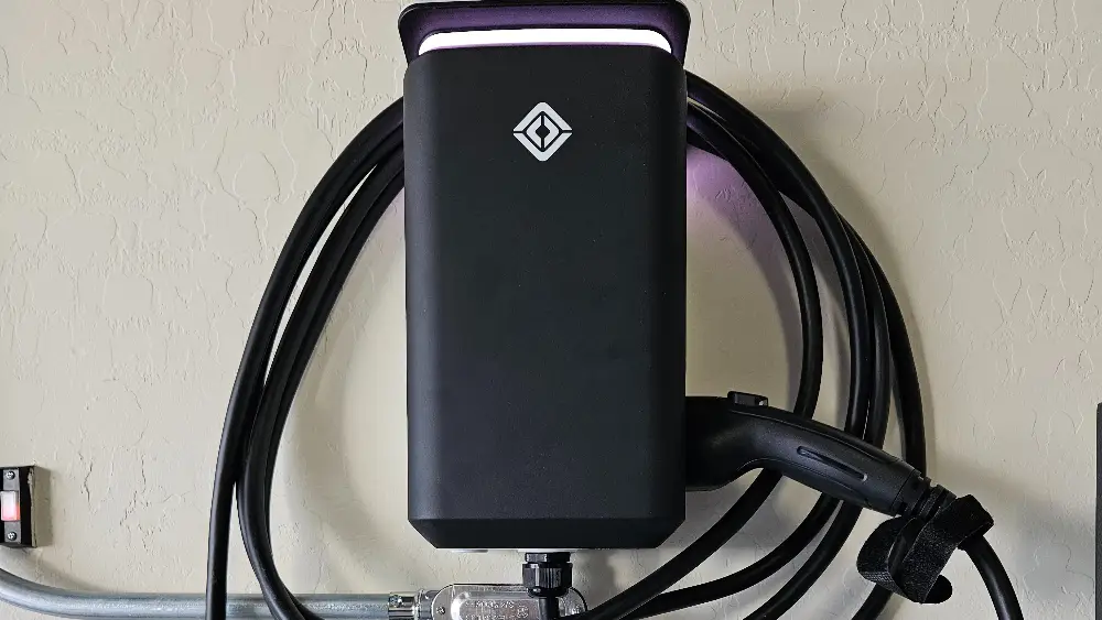 Wall-mounted electric vehicle charging station with a charging cable attached.