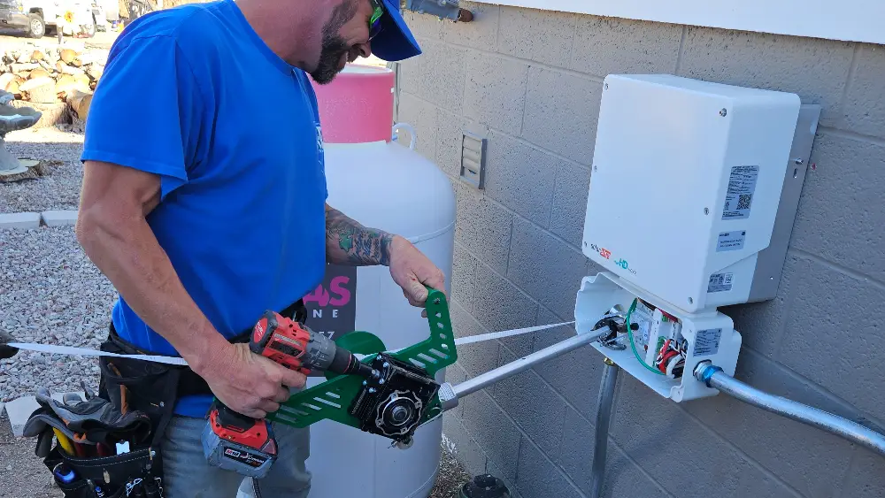 Electrician using a drill to install electrical equipment on a wall.