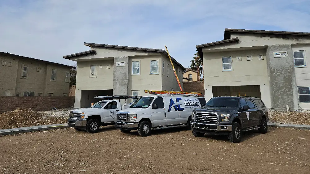 Three construction vehicles parked in front of two residential buildings under construction.
