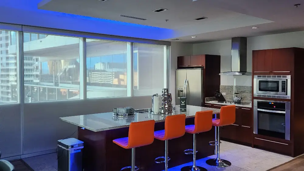 Contemporary kitchen featuring a large island with orange bar stools and stainless steel appliances.