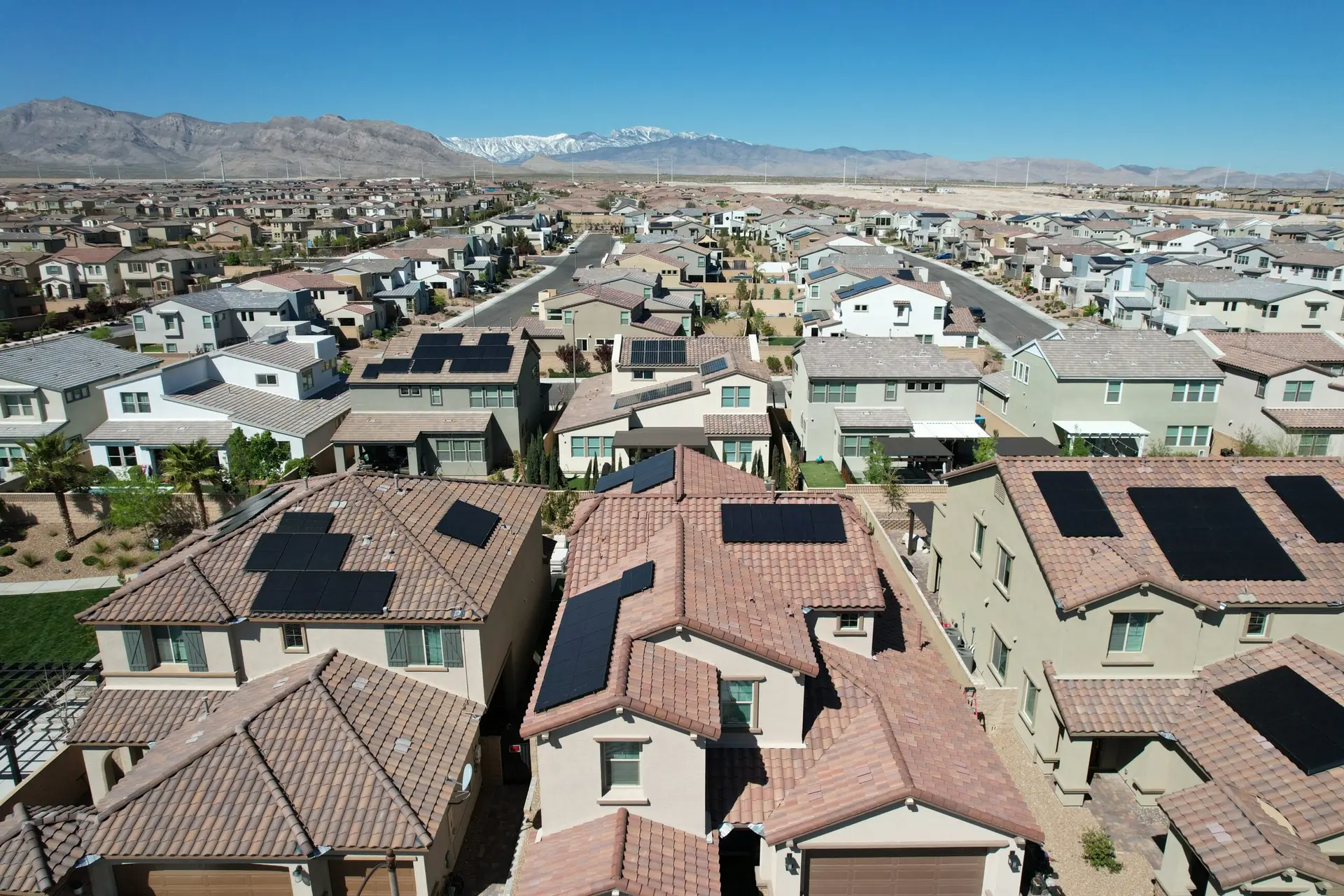 Aerial view of residential neighborhood with multiple houses featuring solar panels on rooftops.