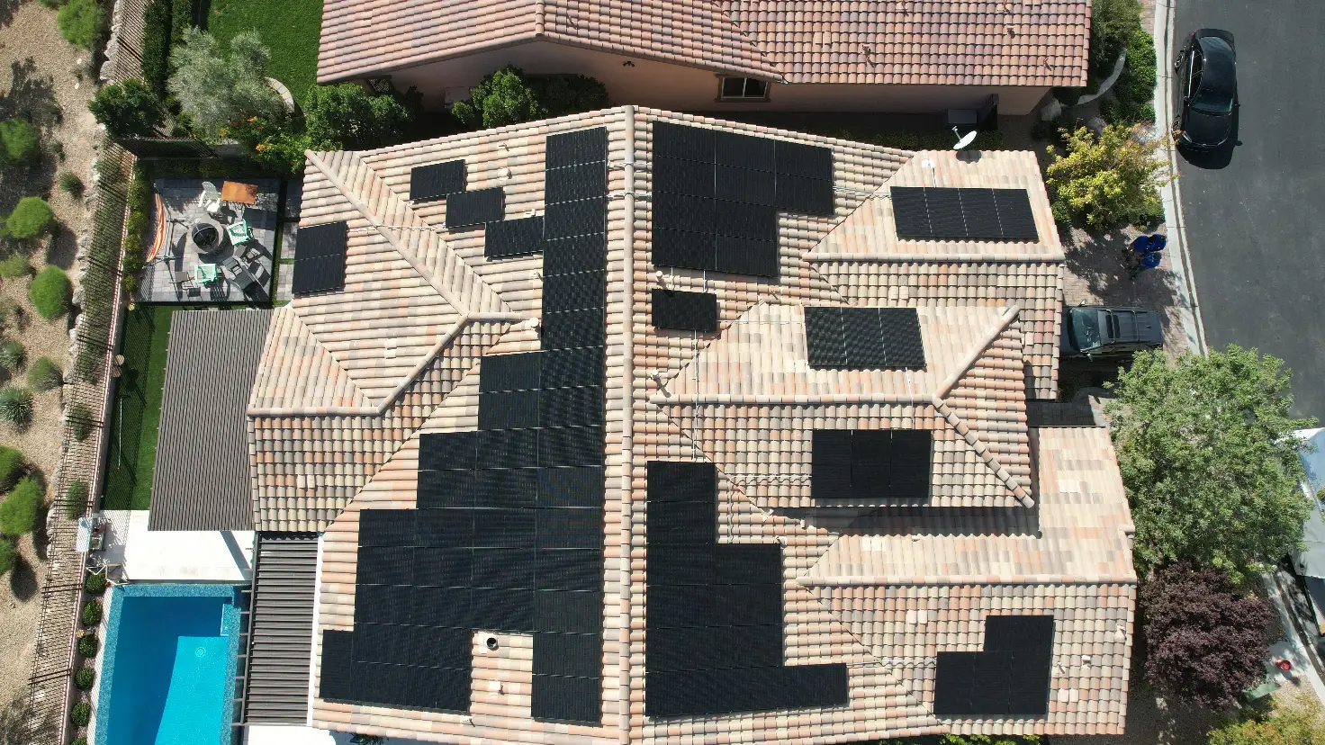 Aerial view of a residential roof covered with solar panels in a patterned layout.